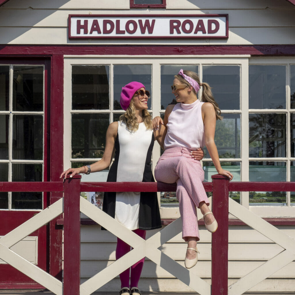 Two Female models sitting and posing on a fence type structure on a signal box building at Hadlow Road disused railway station