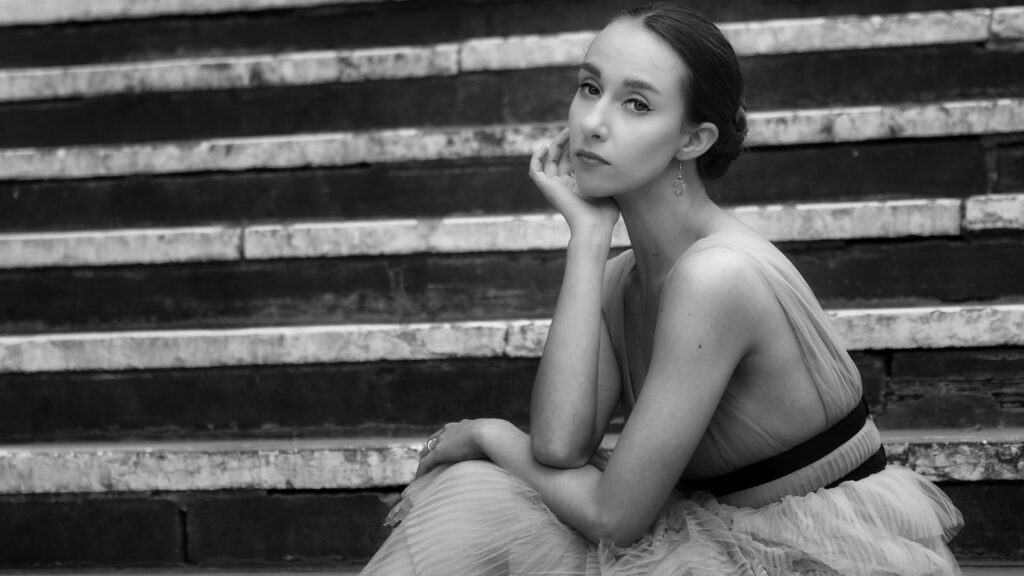 Black and White photo of a female sitting on the steps of the Chester Town Hall (not in picture) with her right hand under her chin and elbow resting on her left arm.